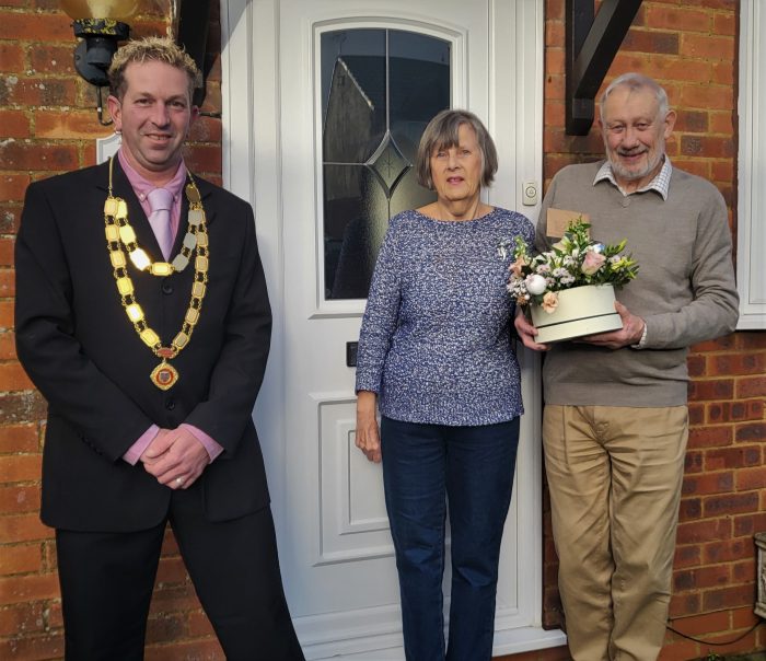 Image of Parish Council Chairman wearing chain of office stood beside man and woman holding flowers