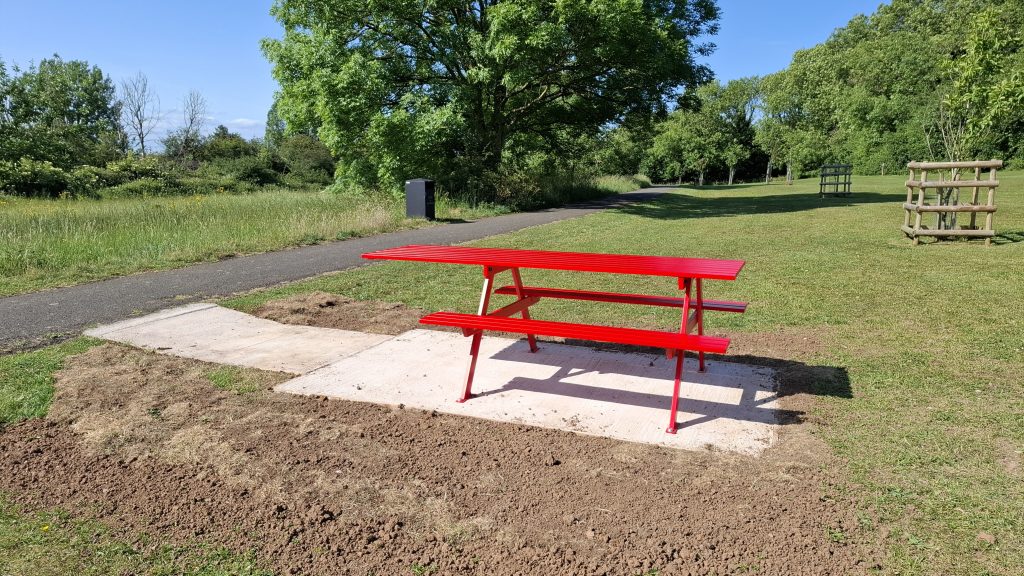 A red picnic bench on common land